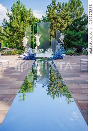 Wedding ceremony decor with mirror carpet, blue and white flowers.  119125888
