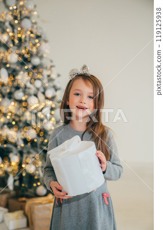 Cute little girl with gift in box and christmas tree 119125938