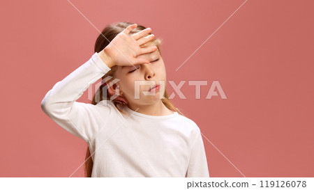 Little charismatic girl dramatically places her hand on her forehead, mimicking exhausted or overwhelmed expression against pastel pink background. 119126078