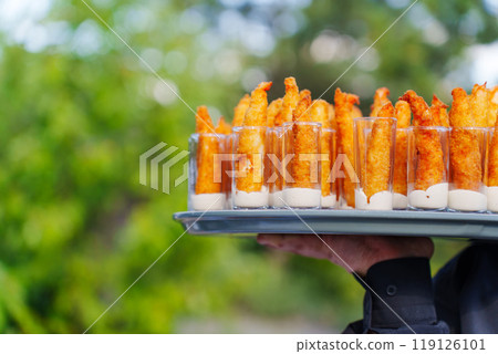 Catering. Men's hands arrange stacks of appetizers of battered shrimp with sauce Catering. Men's hands arrange stacks of appetizers of battered shrimp with sauce 119126101