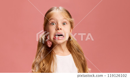 Girl's face shows big, dramatic shocked expression with her eyes and mouth wide open, against pastel pink background. Surprise or disbelief. 119126102