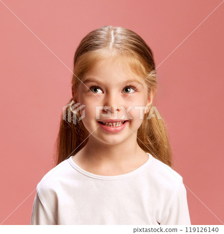 Curious girl looks up, deep in thought against pink studio background. Her playful expression sparks imagination and wonder. 119126140