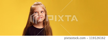 Banner. Girl giving suspicious sideways glance, her expression showing deep thought against yellow studio background with negative space. Banner. Girl giving suspicious sideways glance, her expression showing deep thought against yellow studio background with negative space. 119126162