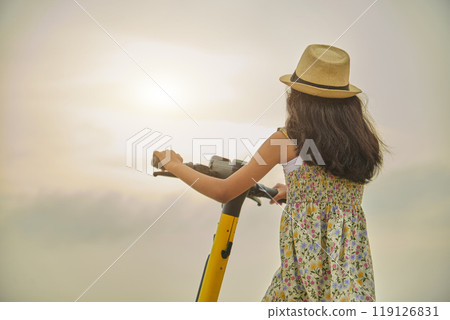 A girl wearing a straw hat is riding a scooter. Summer time A girl wearing a straw hat is riding a scooter. Summer time 119126831