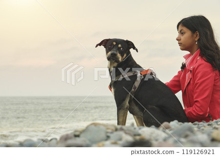 A woman sits on the beach with her dog. Summer time. Selective focus. 119126921