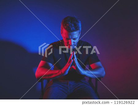 A man is sitting in a chair and praying A man is sitting in a chair and praying 119126922