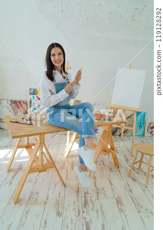 A Joyful Artist Proudly Showcasing Their Colorful Paint Brushes in a Bright and Inspiring Studio Environment 119128292