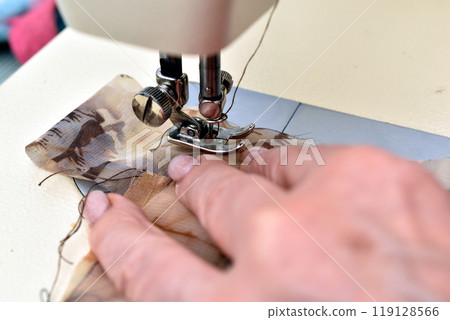 The seamstress works at the sewing machine. The seamstress works at the sewing machine. 119128566