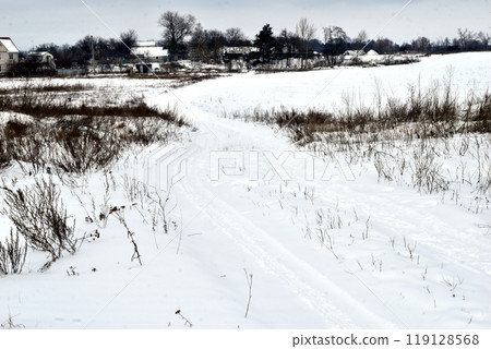 Winter. The country road and field were covered with snow. 119128568