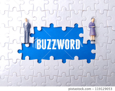 Miniature businessman and business women on a white puzzle with text BUZZWORD. 119129053