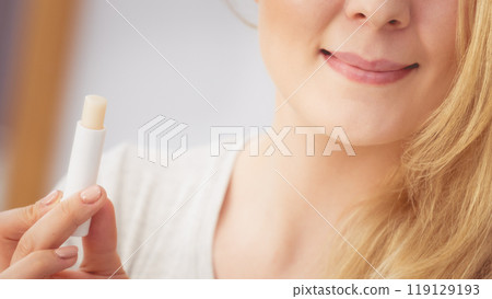 Woman using lip balm on her lips Woman using lip balm on her lips 119129193
