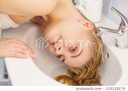 Woman washing hair in bathroom sink Woman washing hair in bathroom sink 119129219