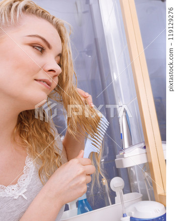 Woman combing her long hair in bathroom 119129276