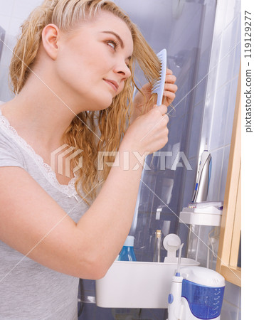 Woman combing her long hair in bathroom 119129277