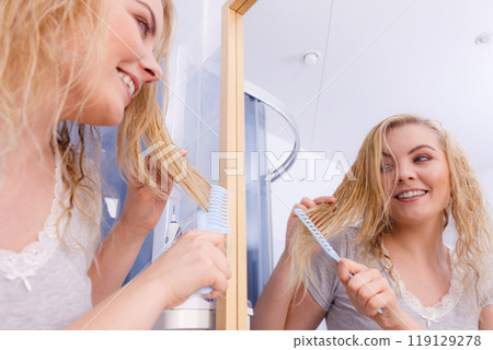 Woman combing her long hair in bathroom 119129278