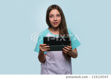 Surprised young girl holding tablet, showing shocked expression. Surprised young girl holding tablet, showing shocked expression. 119129347