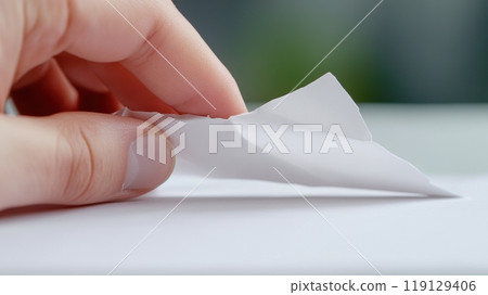 Hand Tearing a Piece of White Paper in a Close-Up View with Soft Focus Background, AI 119129406