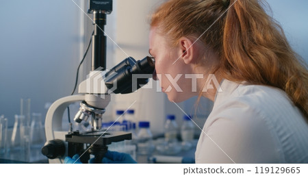 Medical science laboratory: Female biochemist looks under microscope 119129665