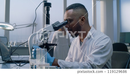 Bright medical science lab: African American microbiologist looks under microscope 119129686