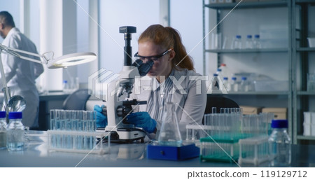 Medical science lab: Female microbiologist looks under microscope Medical science lab: Female microbiologist looks under microscope 119129712