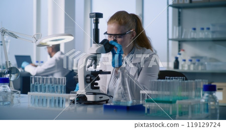 Young female microbiologist takes sample of medicine or vaccine from test tube Young female microbiologist takes sample of medicine or vaccine from test tube 119129724