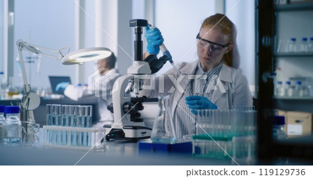 Young female microbiologist takes sample of medicine or vaccine from test tube Young female microbiologist takes sample of medicine or vaccine from test tube 119129736