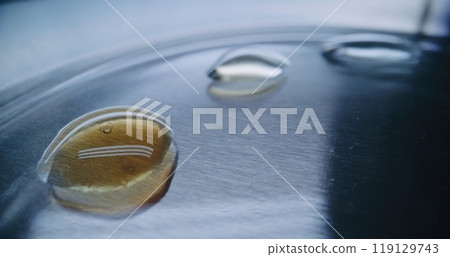 Professional chemist adding liquid in water drops on Petri dish using needle 119129743