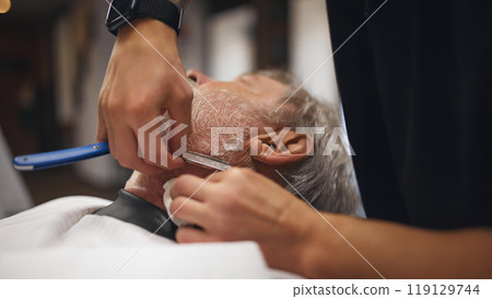 Close-up of barber using straight razor on male neck, carefully shaving around edges. Precision and attention to detail 119129744