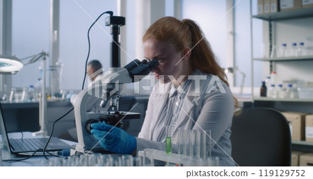 Female scientist wearing protective glasses to analyze new sample under microscope Female scientist wearing protective glasses to analyze new sample under microscope 119129752