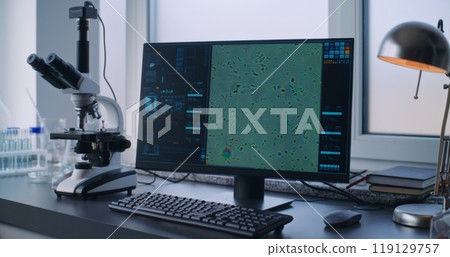 Workplace in medical science laboratory: PC screen shows image of cells from microscope 119129757