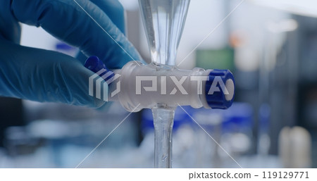 Close up of chemist pouring liquid from pipette into glass bottle 119129771