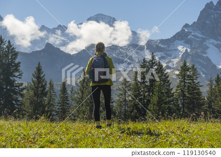 Sporty woman standing in front of snow mountains and enjoying view of Switzerland nature. Wanderlust, sport, beauty in nature. 119130540