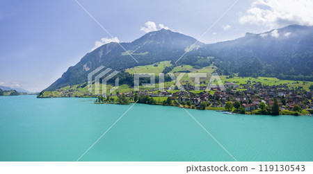 Aerial of Swiss village Lungern with traditional houses, old church Alter Kirchturm along lovely emerald green lake Lungerersee, canton of Obwalden Switzerland Aerial of Swiss village Lungern with traditional houses, old church Alter Kirchturm along lovely emerald green lake Lungerersee, canton of Obwalden Switzerland 119130543
