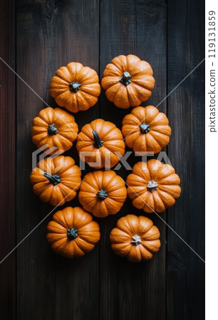 Arrangement of vibrant orange pumpkins on a dark wooden surface in autumn decor Arrangement of vibrant orange pumpkins on a dark wooden surface in autumn decor 119131859