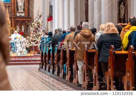 Church altar during Christmas Mass with The Nativity scene. Back view of standing parishioners. The Catholic Orthodox Christmas holiday in Europe Church altar during Christmas Mass with The Nativity scene. Back view of standing parishioners. The Catholic Orthodox Christmas holiday in Europe 119132038