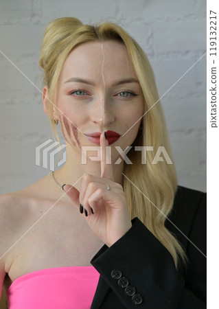 Close-up portrait of a blonde smiling girl with different make-up on half of her face which points to silence on white background Close-up portrait of a blonde smiling girl with different make-up on half of her face which points to silence on white background 119132217