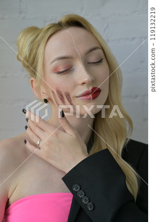 Close-up portrait of a blonde smiling girl with different make-up on half of her face with hand near face on white background Close-up portrait of a blonde smiling girl with different make-up on half of her face with hand near face on white background 119132219
