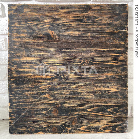 Rustic wooden panel leans gracefully against a textured white brick wall, showcasing its rich grain patterns and natural warmth. Contrast between the organic wood and the structured brick provides a Rustic wooden panel leans gracefully against a textured white brick wall, showcasing its rich grain patterns and natural warmth. Contrast between the organic wood and the structured brick provides a 119132751