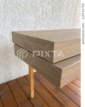 Stacked wooden planks display an exquisite blend of natural texture and modern design. Warm tones and linear grain pattern bring elegance and simplicity to this architectural detail Stacked wooden planks display an exquisite blend of natural texture and modern design. Warm tones and linear grain pattern bring elegance and simplicity to this architectural detail 119132758