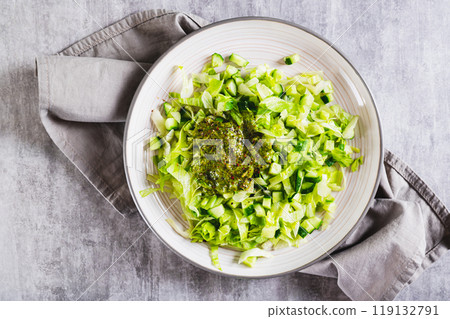 Appetizing salad of cucumber and iceberg lettuce with spices on a plate on the table top view Appetizing salad of cucumber and iceberg lettuce with spices on a plate on the table top view 119132791