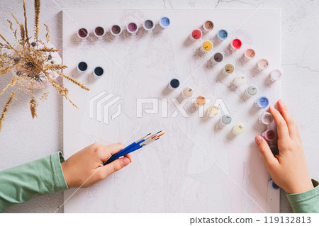 Girl's hands holding brushes and paints for painting by numbers top view Girl's hands holding brushes and paints for painting by numbers top view 119132813