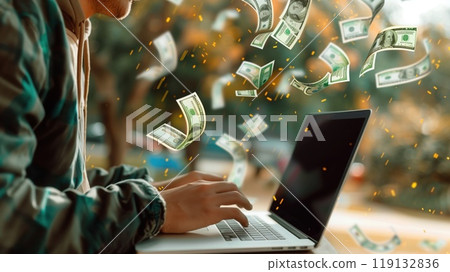 A large plan of a person's hands near an open laptop with money pouring out. The concept of freelancing and quick money 119132836