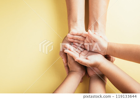Studio shot, Top view close-up of family hands stacked against an isolated background. Parents and children hold an empty space symbolizing support and love on Family and Parents Day. Studio shot, Top view close-up of family hands stacked against an isolated background. Parents and children hold an empty space symbolizing support and love on Family and Parents Day. 119133644