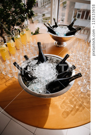 Chilled champagne bottles in ice bucket with lemonade pitchers and glasses on the table 119133658