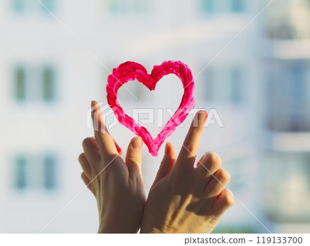 Fingers draw red heart sign on the window glass in sunlight. The concept of Valentine's Day, romantic relationships, Gift Red heart emotional. Closing feelings, lonelyness. Revealing feelings, trust. Fingers draw red heart sign on the window glass in sunlight. The concept of Valentine's Day, romantic relationships, Gift Red heart emotional. Closing feelings, lonelyness. Revealing feelings, trust. 119133700