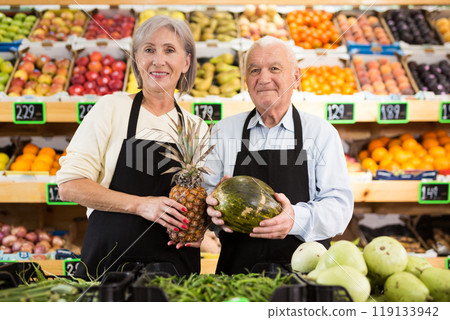 Portrait of satisfied two supermarket employee with fruit in hands in sales floor Portrait of satisfied two supermarket employee with fruit in hands in sales floor 119133942
