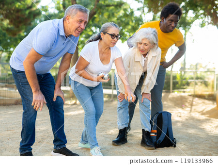 A group of multiracial mature adult people playing patanque game outdoors in a park A group of multiracial mature adult people playing patanque game outdoors in a park 119133966