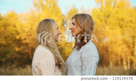 Happy two women, smiling mature mother and adult daughter hugging in autumn park 119134378