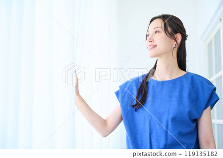Young woman standing by the window 119135182