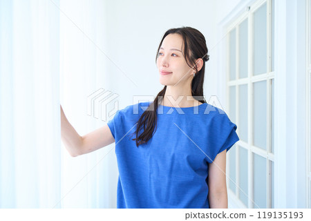 Young woman standing by the window Young woman standing by the window 119135193